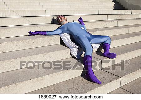 Stock Photo - Man dressed as superhero lying on steps. Fotosearch