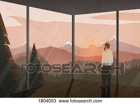 Stock Image - Man enjoying tranquil view of sunset behind mountains from glass house. Fotosearch