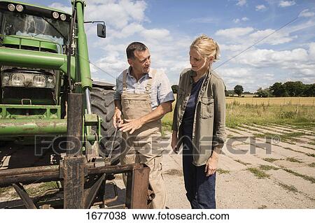 Man explaining woman while standing by agricultural machinery at farm View Large Photo Image Stock Photo - Man explaining woman while standing by agricultural machinery at farm. Fotosearch