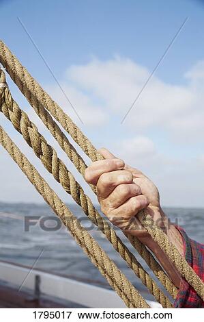 Man holding rope, adjusting rigging on boat View Large Photo Image Stock Photo - Man holding rope, adjusting rigging on boat. Fotosearch