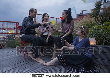 Man serving red wine to female friend during party on patio View Large Photo Image Stock Photo - Man serving red wine to female friend during party on patio. Fotosearch