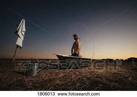 Man splashing wet hair in bathtub in rural field View Large Photo Image Stock Image - Man splashing wet hair in bathtub in rural field. Fotosearch