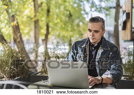Man using laptop at sidewalk cafe View Large Photo Image Stock Image - Man using laptop at sidewalk cafe. Fotosearch