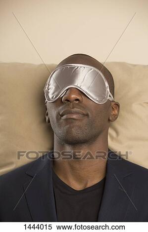 Man wearing eye mask while sleeping on sofa against colored background View Large Photo Image Stock Photography - Man wearing eye mask while sleeping on sofa against colored background. Fotosearch