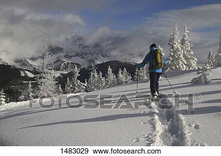 Man wearing warm clothing walking on snow covered field against mountains View Large Photo Image Stock Photo - Man wearing warm clothing walking on snow covered field against mountains. Fotosearch