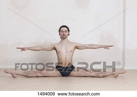 Man with arms outstretched doing splits while performing yoga against white background View Large Photo Image Stock Photo - Man with arms outstretched doing splits while performing yoga against white background. Fotosearch
