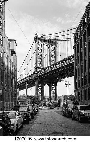 Stock Photograph - Manhattan Bridge against sky seen from street in city, New York City, New York, USA. Fotosearch