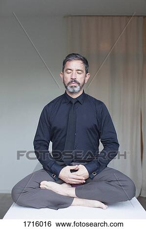 Mature businessman meditating at home View Large Photo Image Stock Photograph - Mature businessman meditating at home. Fotosearch