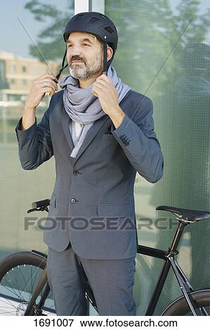 Mature businessman wearing cycle helmet while standing against glass window View Large Photo Image Stock Photo - Mature businessman wearing cycle helmet while standing against glass window. Fotosearch