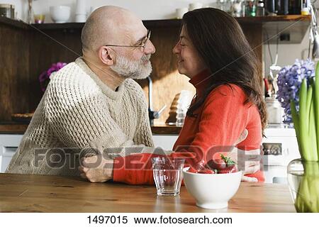Mature couple embracing by table in kitchen at home View Large Photo Image Stock Photography - Mature couple embracing by table in kitchen at home. Fotosearch