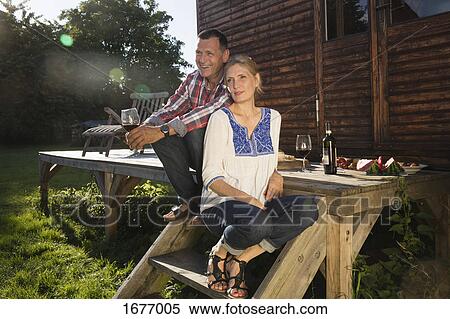 Mature couple enjoying wine while sitting outside farmhouse View Large Photo Image Stock Photography - Mature couple enjoying wine while sitting outside farmhouse. Fotosearch