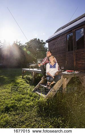 Mature couple relaxing while having wine outside farmhouse during sunny day View Large Photo Image Stock Photography - Mature couple relaxing while having wine outside farmhouse during sunny day. Fotosearch