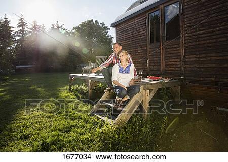 Mature couple resting while having wine outside farmhouse View Large Photo Image Picture - Mature couple resting while having wine outside farmhouse. Fotosearch