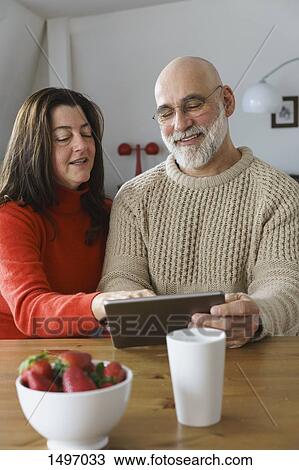 Mature couple using digital tablet on table at home View Large Photo Image Stock Image - Mature couple using digital tablet on table at home. Fotosearch