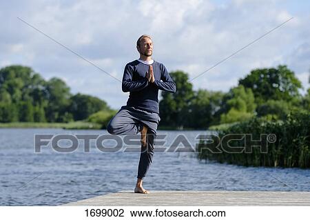 Mature man practicing tree pose yoga on pier by lake against sky View Large Photo Image Stock Image - Mature man practicing tree pose yoga on pier by lake against sky. Fotosearch
