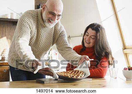 Mature man serving pie to wife on table at home View Large Photo Image Picture - Mature man serving pie to wife on table at home. Fotosearch