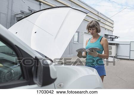 Mature woman reading manual while standing by breakdown car View Large Photo Image Stock Image - Mature woman reading manual while standing by breakdown car. Fotosearch