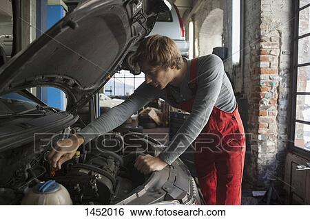 Mechanic examining car engine at auto repair shop View Large Photo Image Stock Photograph - Mechanic examining car engine at auto repair shop. Fotosearch