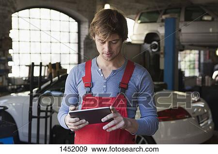 Stock Photo - Mechanic using digital tablet at garage. Fotosearch