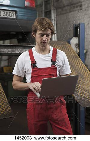 Mechanic using laptop at garage View Large Photo Image Stock Image - Mechanic using laptop at garage. Fotosearch