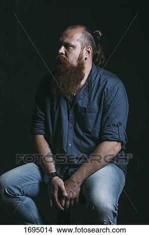 Mid adult hipster looking away while sitting against black background View Large Photo Image Picture - Mid adult hipster looking away while sitting against black background. Fotosearch