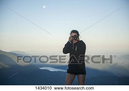 Mid adult woman photographing with mountains in background View Large Photo Image Stock Image - Mid adult woman photographing with mountains in background. Fotosearch