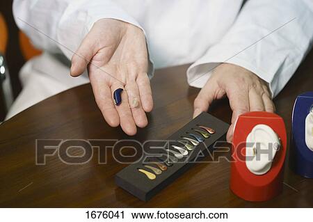 Midsection of audiologist showing hearing aid while sitting at office in office View Large Photo Image Stock Image - Midsection of audiologist showing hearing aid while sitting at office in office. Fotosearch