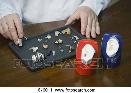 Midsection of audiologist various hearing aids at table in doctor's office View Large Photo Image Stock Image - Midsection of audiologist various hearing aids at table in doctor's office. Fotosearch