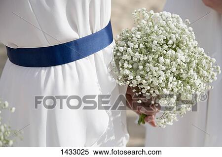 Stock Photography - Midsection of bride holding flowers outdoors. Fotosearch