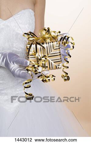 Midsection of bride holding gift box against colored background View Large Photo Image Stock Image - Midsection of bride holding gift box against colored background. Fotosearch