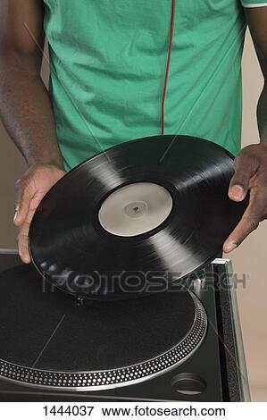 Stock Photo - Midsection of DJ putting record on turntable. Fotosearch