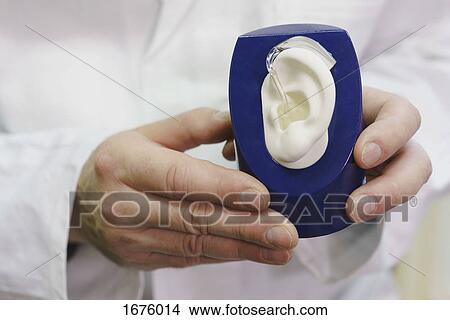 Midsection of doctor holding anatomical model with hearing aid at office View Large Photo Image Picture - Midsection of doctor holding anatomical model with hearing aid at office. Fotosearch