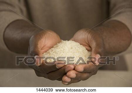 Stock Photo - Midsection of man holding rice in cupped hands. Fotosearch