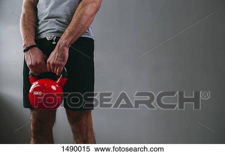 Midsection of man lifting kettlebell at gym View Large Photo Image Stock Photography - Midsection of man lifting kettlebell at gym. Fotosearch
