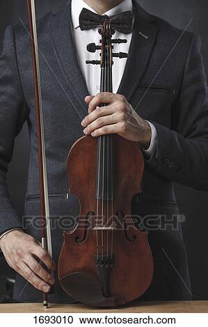 Midsection of violinist holding violin at table against black background View Large Photo Image Stock Image - Midsection of violinist holding violin at table against black background. Fotosearch