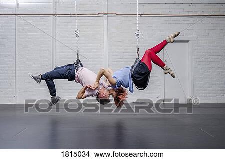 Picture - Modern aerialist dancers performing, hanging upside-down and kissing. Fotosearch