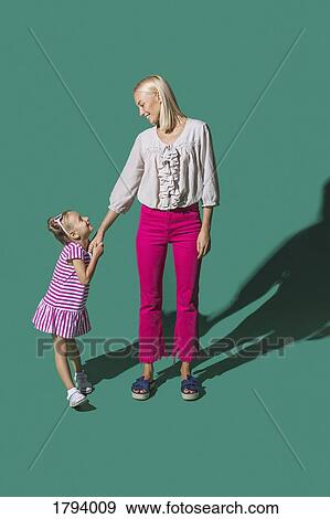 Mother and daughter holding hands on green background View Large Photo Image Stock Photo - Mother and daughter holding hands on green background. Fotosearch