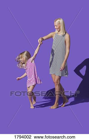 Mother and daughter in striped dresses dancing on purple background View Large Photo Image Stock Image - Mother and daughter in striped dresses dancing on purple background. Fotosearch