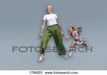 Mother and daughter running on blue background View Large Photo Image Stock Image - Mother and daughter running on blue background. Fotosearch