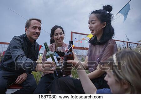 Multi-ethnic friends toasting wine bottles during party on patio View Large Photo Image Stock Image - Multi-ethnic friends toasting wine bottles during party on patio. Fotosearch