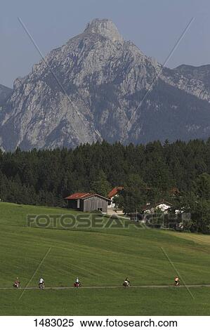 People riding bicycle on road amidst grassy field against mountain View Large Photo Image Stock Photography - People riding bicycle on road amidst grassy field against mountain. Fotosearch