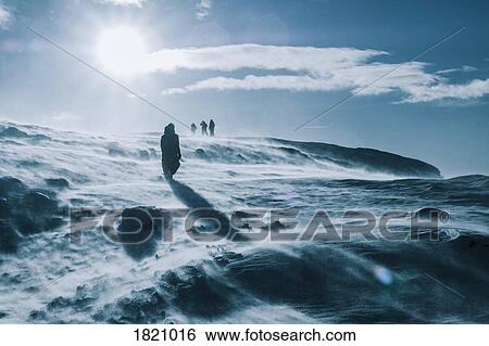 People walking across sunny, windy, snow covered landscape, Reykjadalur, Iceland View Large Photo Image Stock Photograph - People walking across sunny, windy, snow covered landscape, Reykjadalur, Iceland. Fotosearch