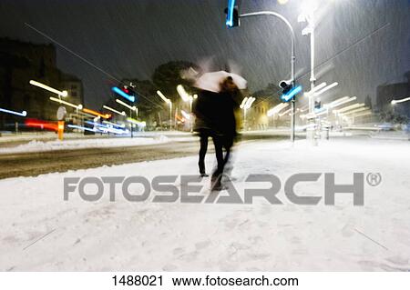 People walking in city during snow storm at night View Large Photo Image Stock Image - People walking in city during snow storm at night. Fotosearch