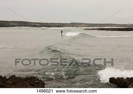 Stock Image - Person surfing at beach, Vila Nova de Milfontes, Portugal. Fotosearch