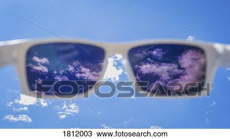 Stock Image - Personal perspective sunglasses looking up at sunny blue sky with clouds. Fotosearch