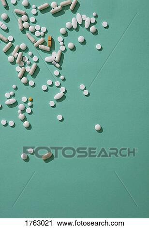 Stock Image - Pills scattered on green background. Fotosearch