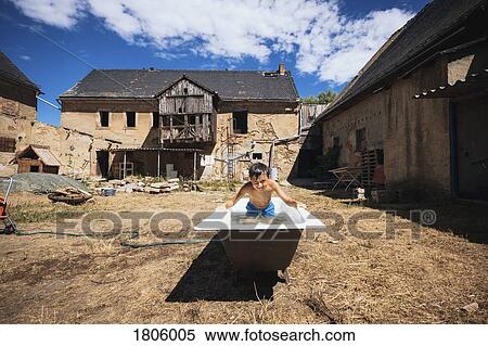 Playful boy in bathtub on sunny rural farm View Large Photo Image Stock Photography - Playful boy in bathtub on sunny rural farm. Fotosearch