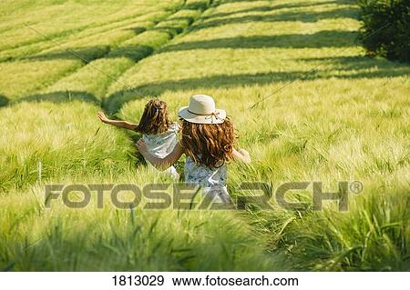 Playful, carefree girls running in sunny, idyllic rural green wheat field View Large Photo Image Stock Photo - Playful, carefree girls running in sunny, idyllic rural green wheat field. Fotosearch
