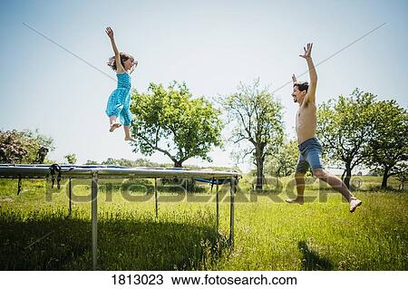 Playful father and daughter jumping on trampoline in sunny summer back yard View Large Photo Image Stock Image - Playful father and daughter jumping on trampoline in sunny summer back yard. Fotosearch