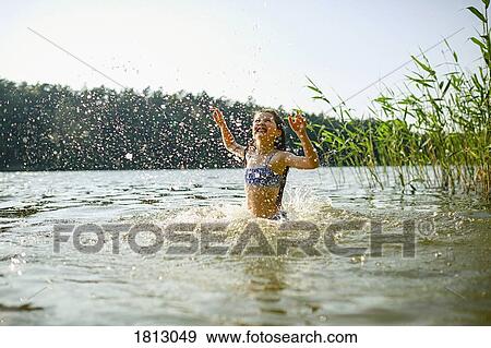 Playful girl splashing, swimming in sunny summer lake View Large Photo Image Stock Photo - Playful girl splashing, swimming in sunny summer lake. Fotosearch